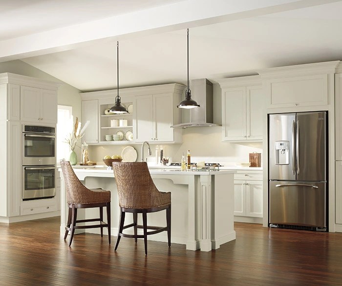 Kemper kitchen in an off-white finish with an island, pendant lighting and wicker stools