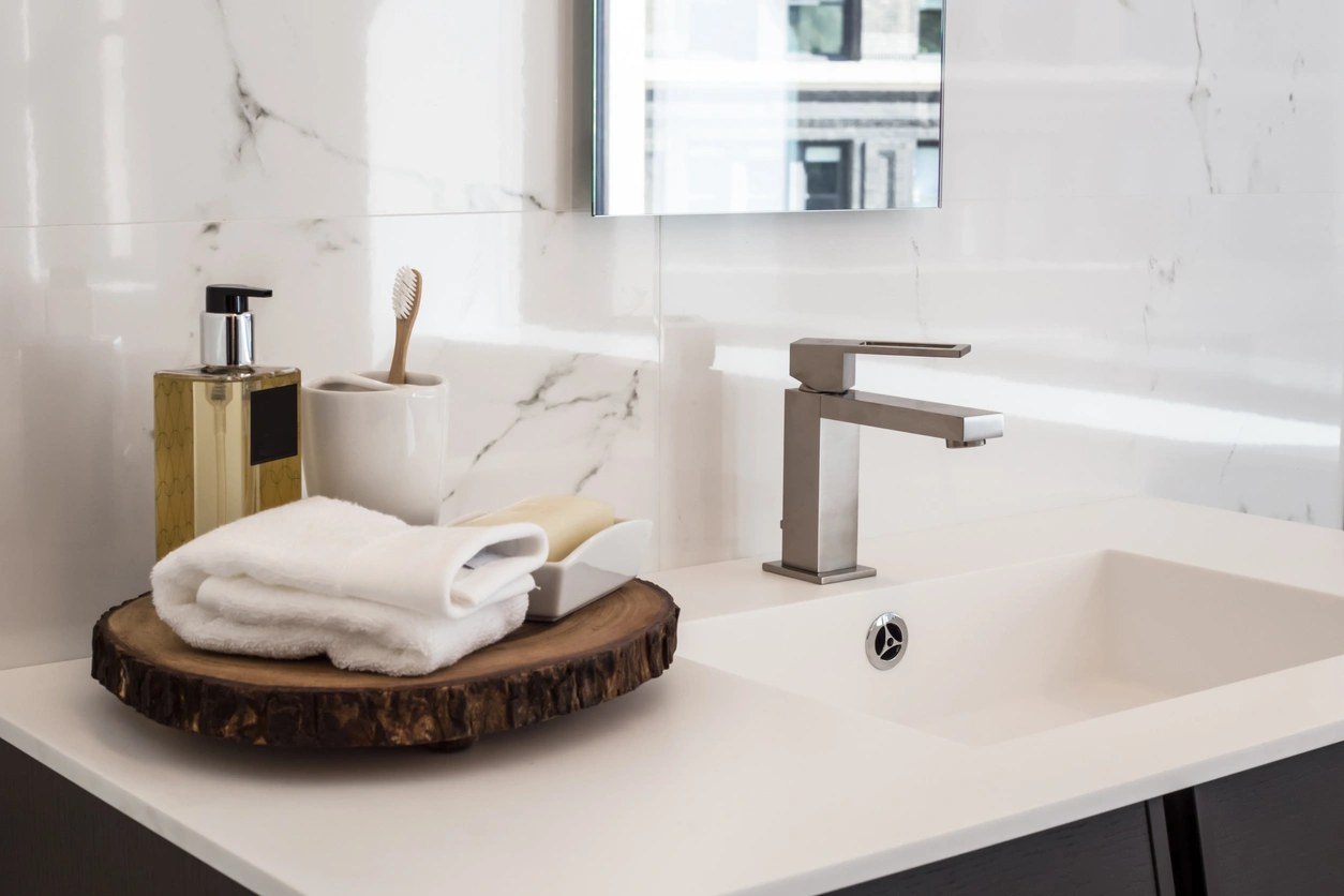 Bathroom vanity with a white stone top, marble wall tile and a brushed nickel faucet